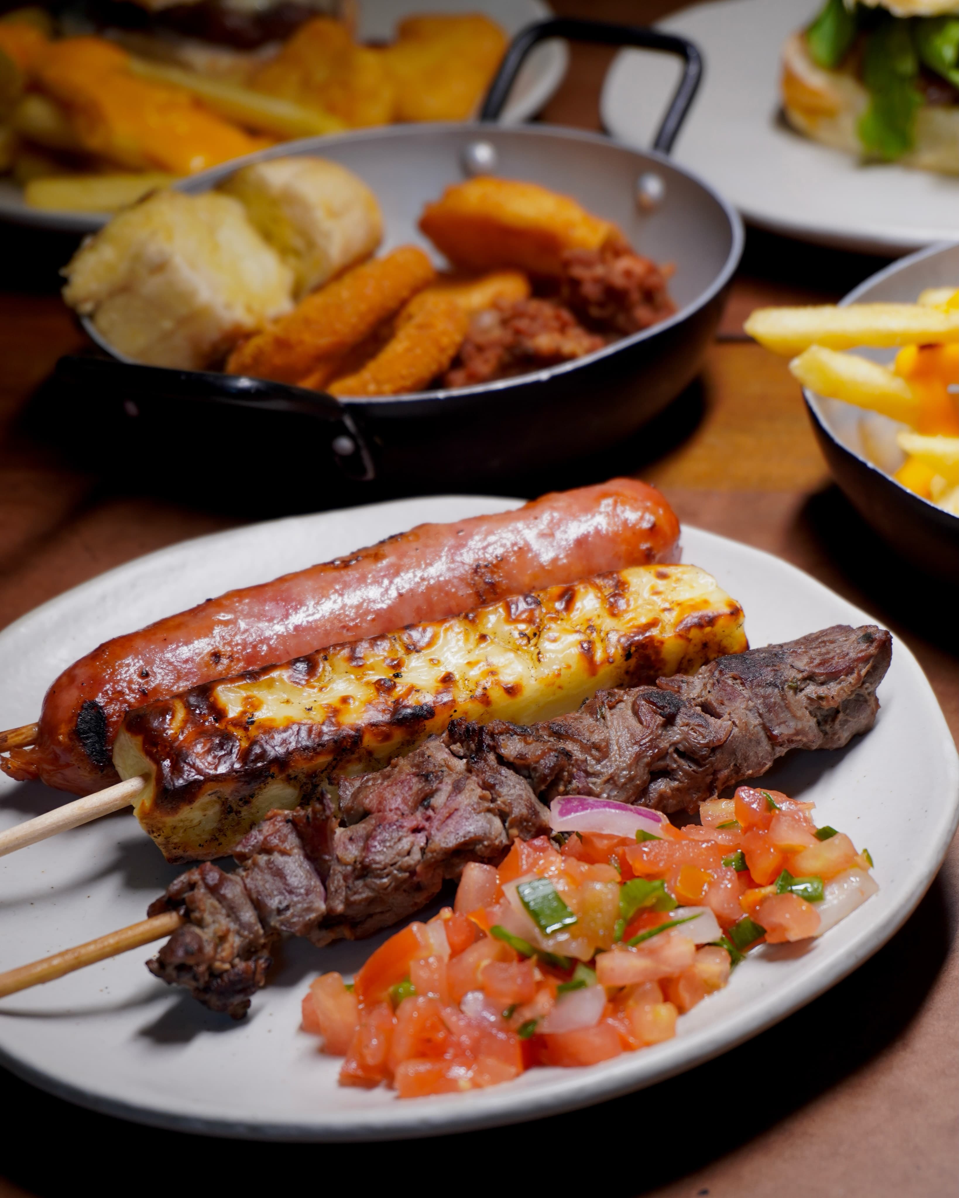 Espetinhos de linguiça, queijo coalho e carne com vinagrete no prato